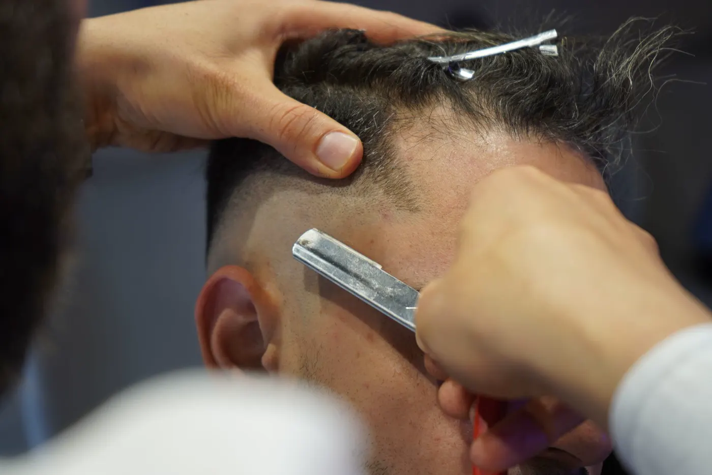 Barbero perfilando la nuca con navaja