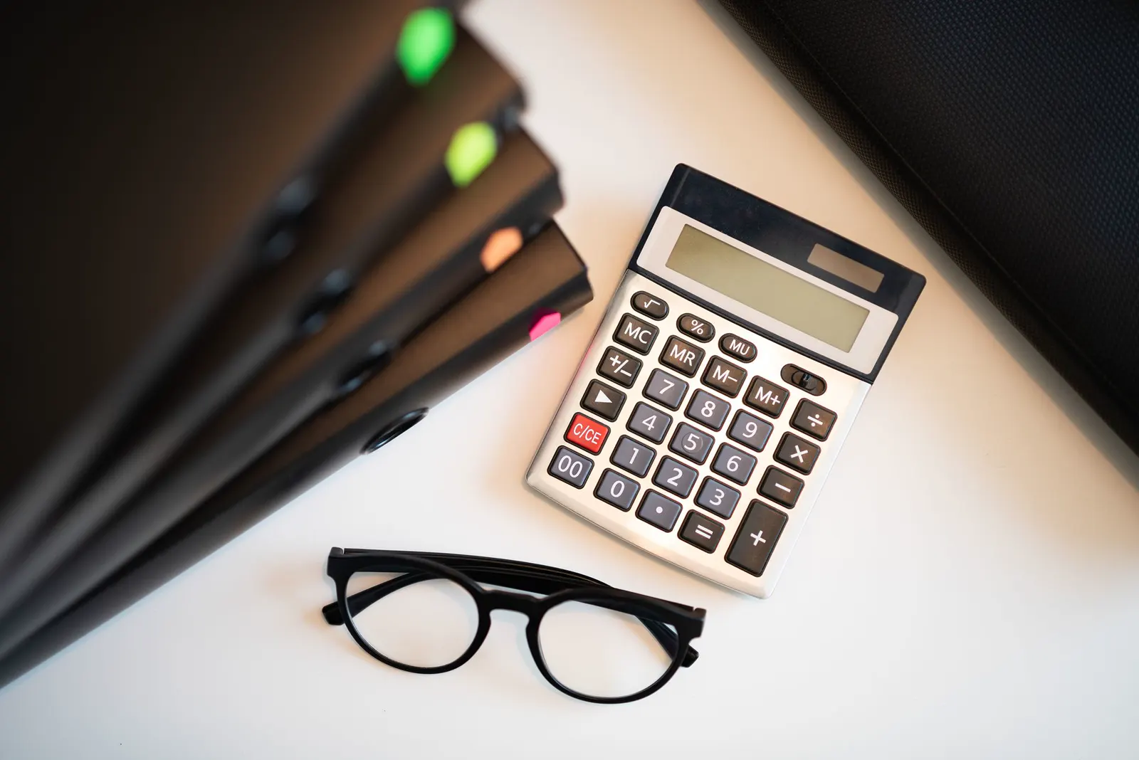 Escritorio blanco con calculadora, lentes y carpetas