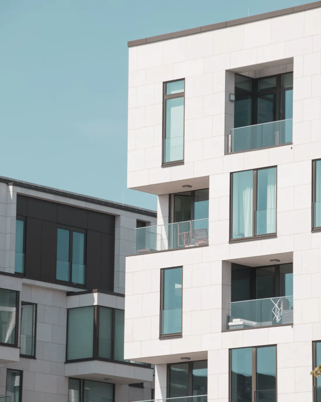 Fachada blanca de un edificio moderno con balcones y ventanas amplias