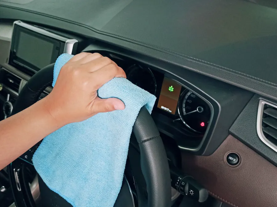 Mano limpiando el tablero de un auto con un paño