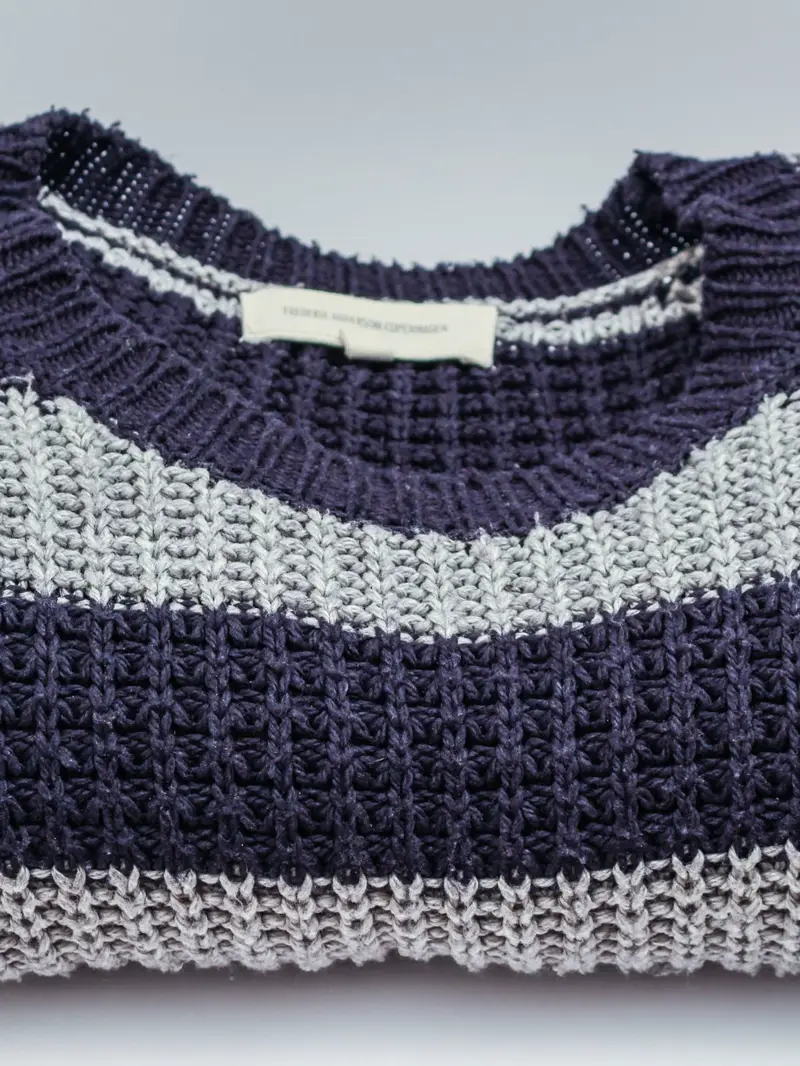 Chompa tejida a rayas azul marino y gris, doblada